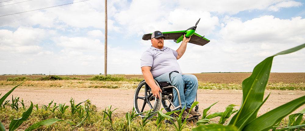 坐在轮椅上的男子准备在农场上空发射无人机.